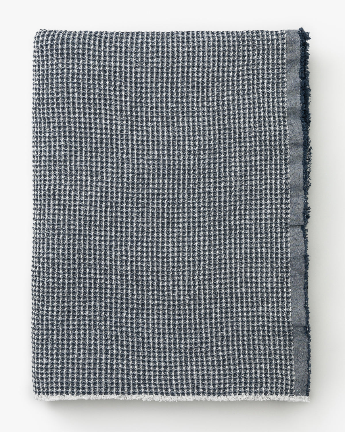 The Rebecca Throw is a dark blue and white waffle weave blanket with a solid blue border, styled like a cozy cotton throw and displayed against a white background.