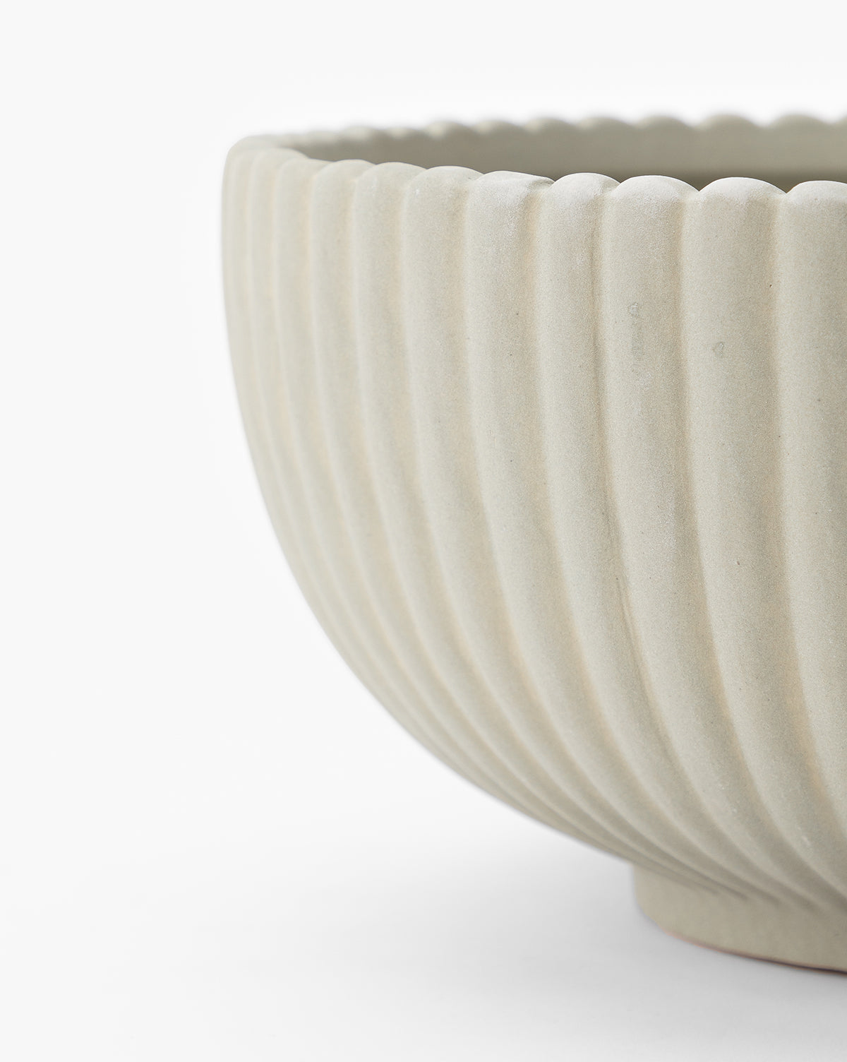 Close-up of the Reeded Bowl in green-tinted beige, featuring vertical ribbing and a scalloped rim, shown against a plain white background.