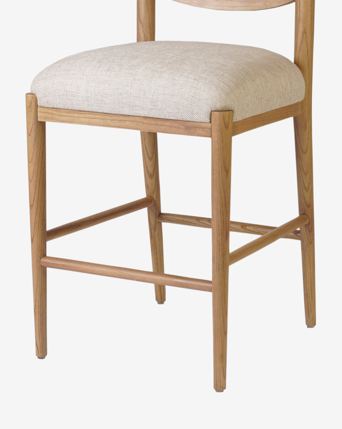 The Four Hands Reverie Stool features natural light brown wood legs and a beige upholstered seat, shown from a front-side angle—ideal for bringing warmth to your kitchen space. McGee & Co.