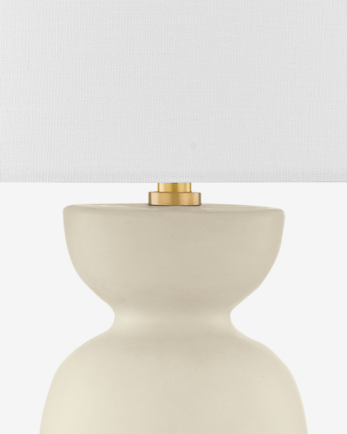The Rhea Table Lamp features a smooth, cream ceramic base with a curved sculptural design, a white textured fabric shade, and a brass accent at the top. Its neutral tones easily complement any décor, by McGee & Co.