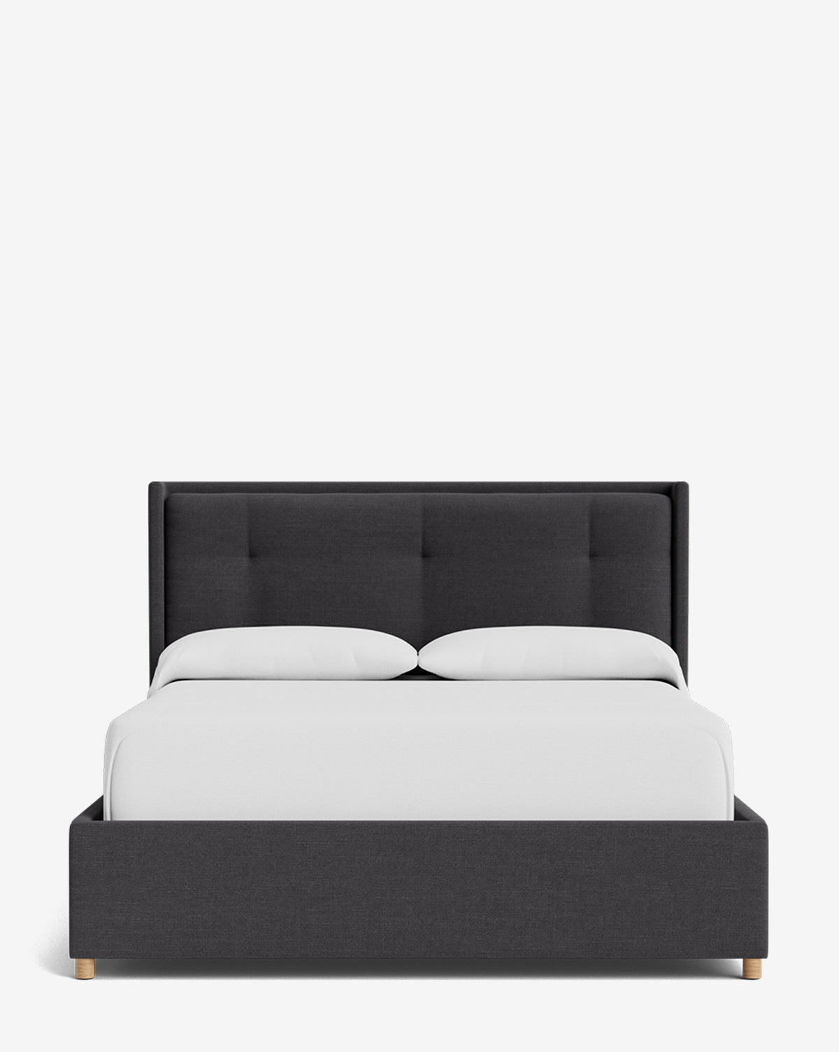 The Ria Bed Low Headboard is a modern, dark gray upholstered frame with a tufted headboard, styled with crisp white bedding and two pillows, displayed against a plain white background by McGee & Co.