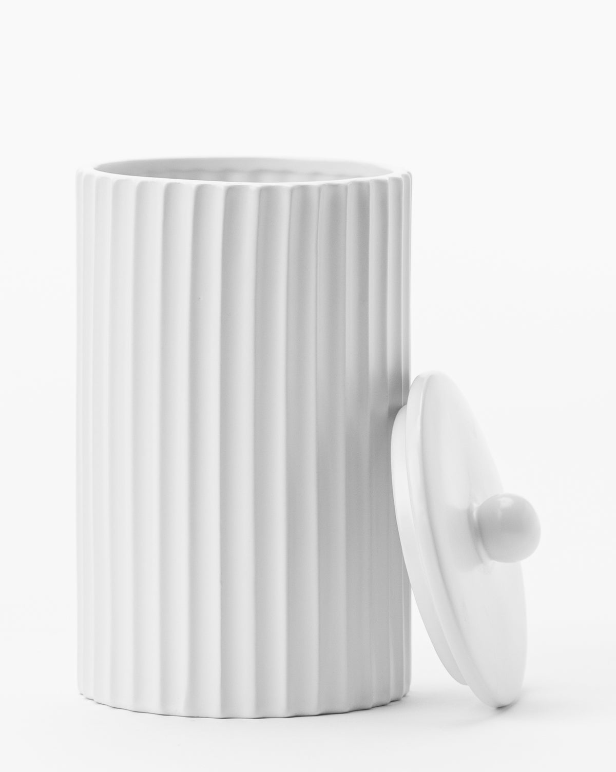 The Fluted Lidded Bathroom Canister, featuring white vertical ridges and a round lid with a knob handle, is displayed on a white background—an elegant accessory for your bathroom.