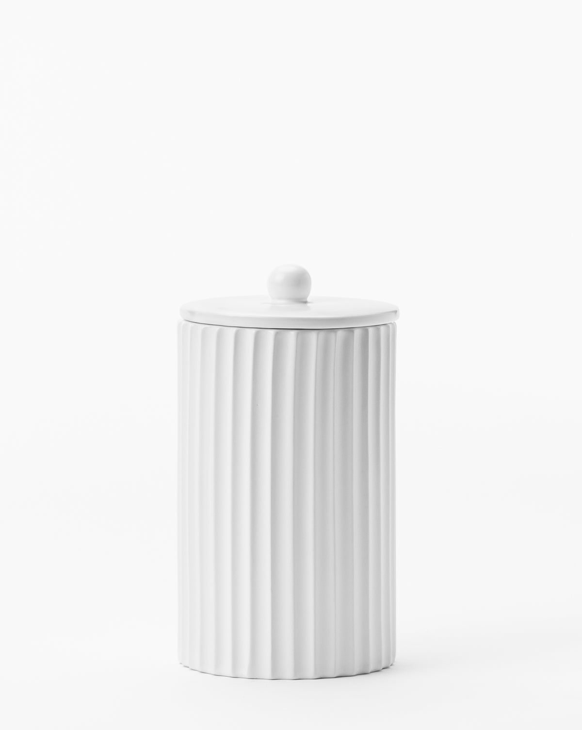 The Fluted Lidded Bathroom Canister is a tall white ceramic cylinder with vertical ridges and a matching lid featuring a round handle—an elegant, functional accessory for any bathroom.