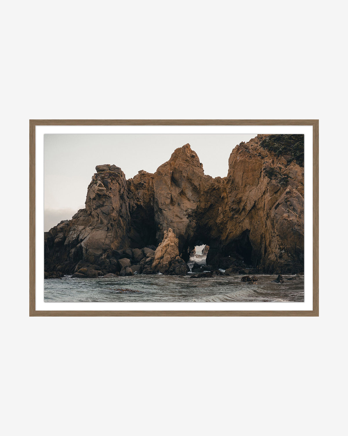 The Rock Formation framed photograph showcases dramatic brown shoreline cliffs with a natural archway, set against ocean waters under a cloudy sky.