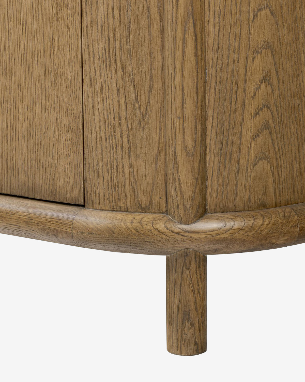 Close-up of the Rolette Sideboards lower corner, featuring vertical oak wood grain, a rounded edge, and a cylindrical leg. The light brown finish emphasizes the natural wood texture, by McGee & Co.