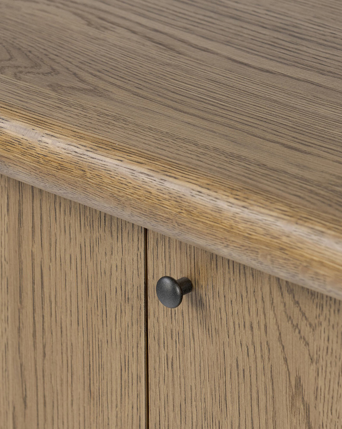 Close-up of the Rolette Sideboard, showcasing its smooth oak grain finish. Rounded edges and bold gunmetal door pulls add a modern accent to this classic piece, by McGee & Co.