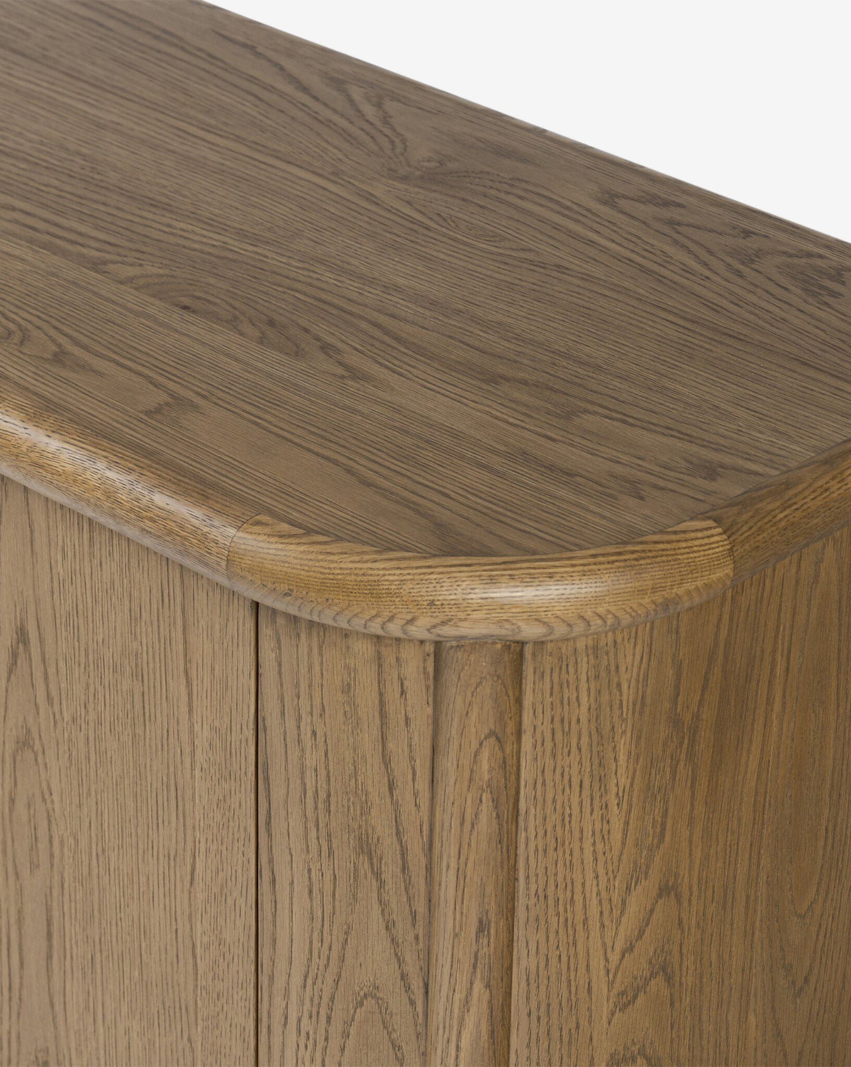 Close-up of the Rolette Sideboard’s corner reveals a rounded edge, visible oak grain, smooth craftsmanship, natural finish, and sleek gunmetal door pulls, by McGee & Co.