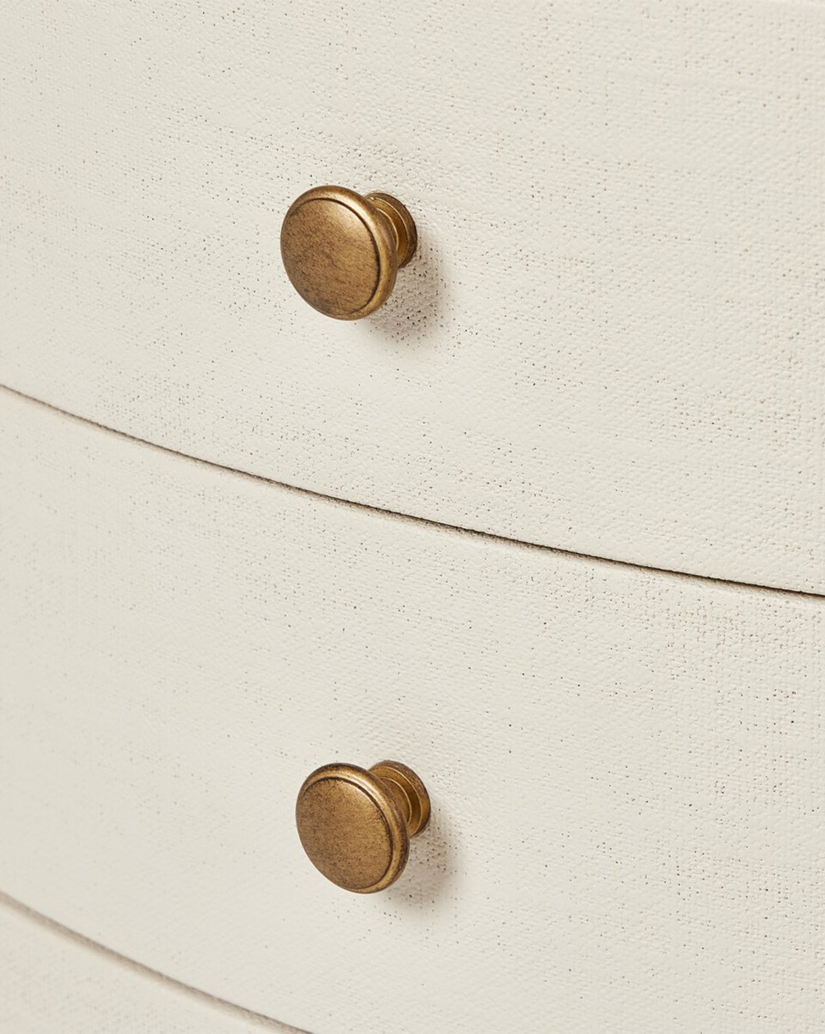 Close-up of two round, brass-colored knobs on the Rosalie Nightstand, featuring an ivory-painted, fabric-textured finish—perfect for adding stylish bedside storage by McGee & Co.