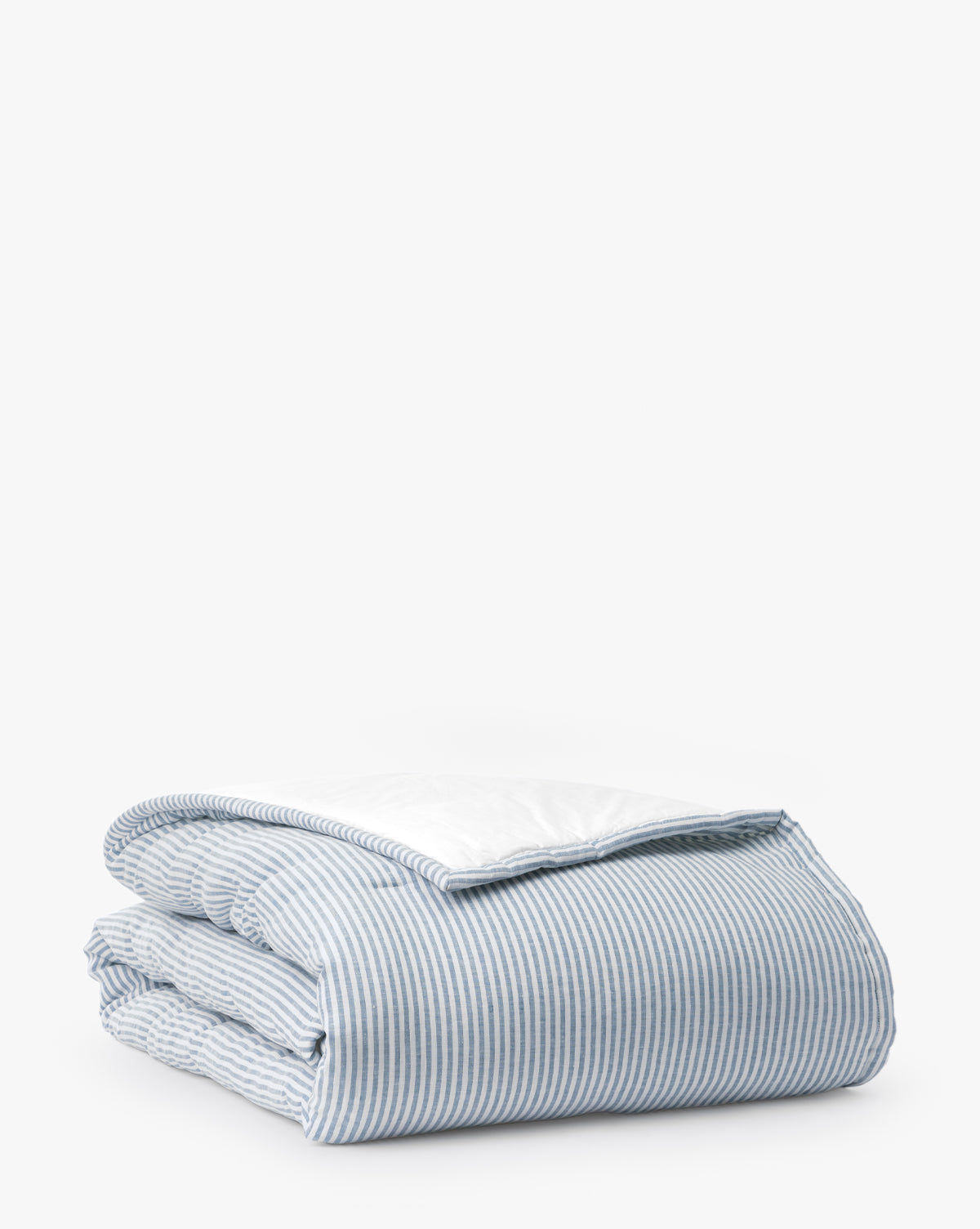 The Rosemary Quilt, made from yarn-dyed fabric with blue and white vertical pinstripes and a white underside, is shown folded against a plain white background.