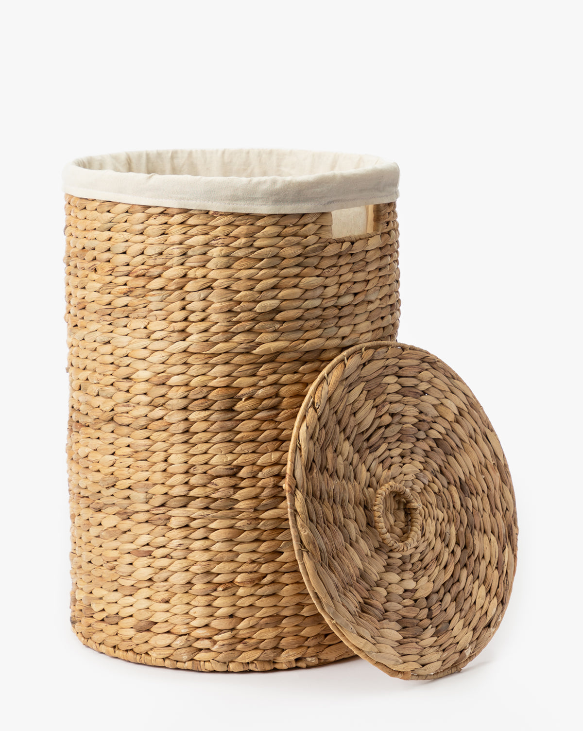 The Round Water Hyacinth Basket is a woven wicker laundry basket crafted from natural materials, featuring a fabric-lined interior and matching lid, shown on a white background.