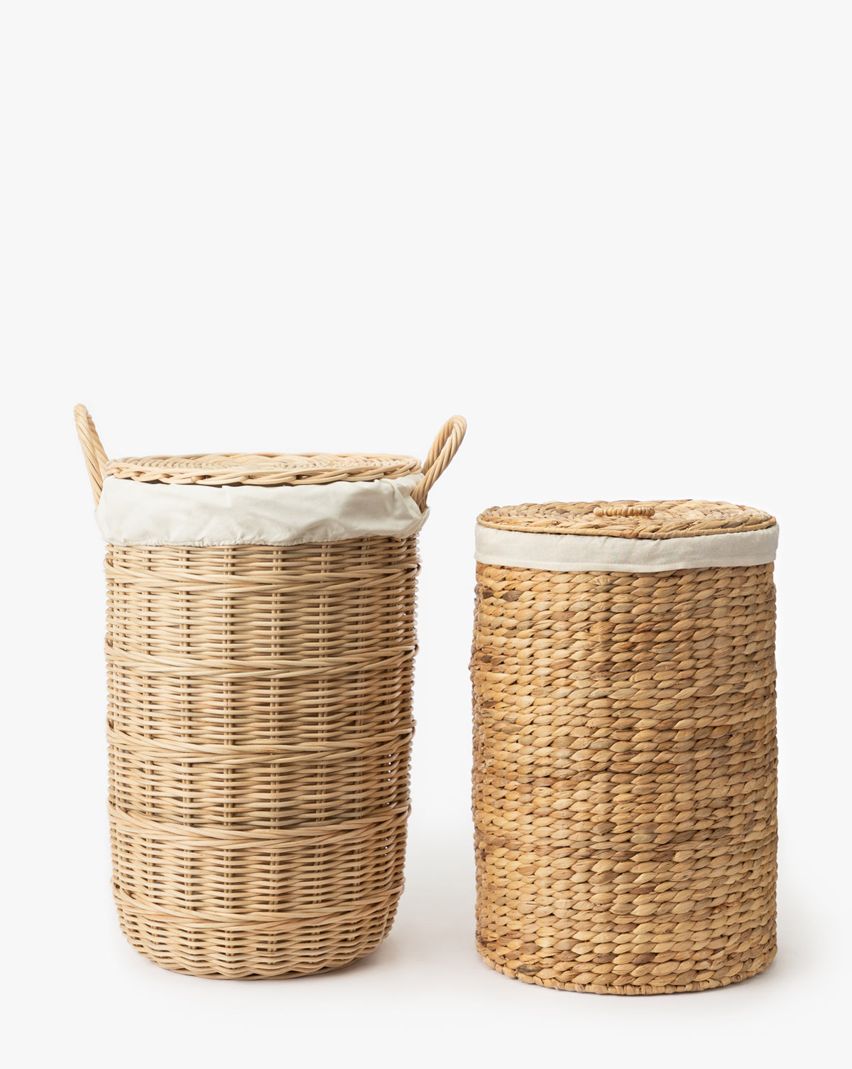 The Round Water Hyacinth Basket, made from natural materials, features a rounded shape with horizontal weaving, a lid, and white fabric lining. It’s displayed on a white background alongside another woven wicker basket.