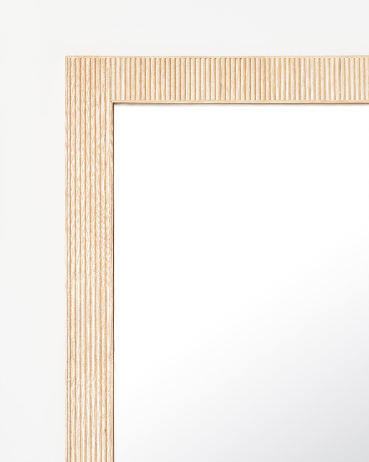 Close-up of the top left corner of the Rowan Floor Mirror, highlighting its ribbed oak frame with vertical texture set against a plain white background, by McGee & Co.