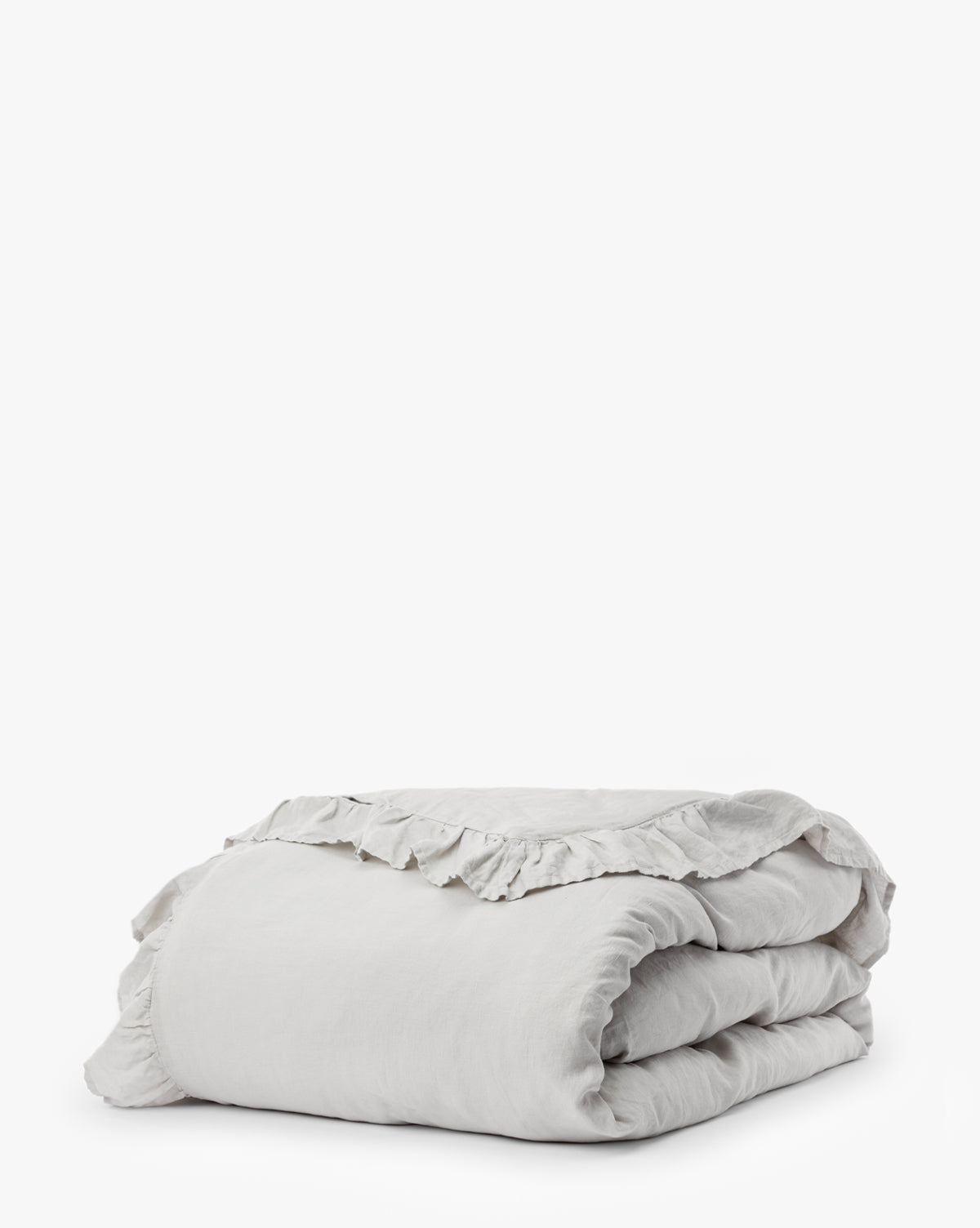 The Ruffle Linen Duvet Cover, crafted from 100% linen in light gray with soft ruffled edges, is neatly folded and displayed on a plain white background.
