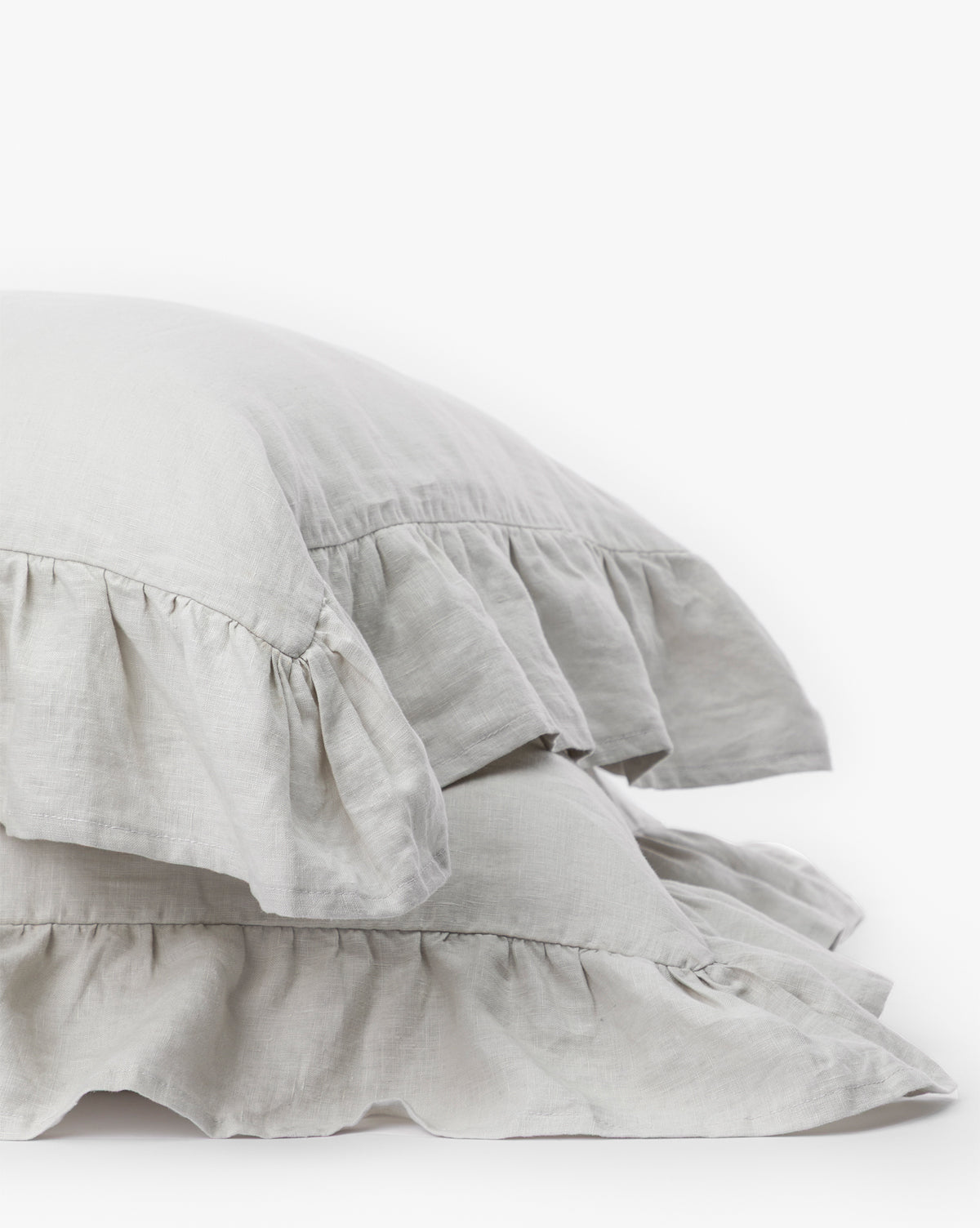 Two light gray Ruffle Linen Shams (Set of 2) are stacked against a white background, showcasing their soft textured linen fabric and romantic ruffled edges—perfect for adding decorative charm to your bedding.