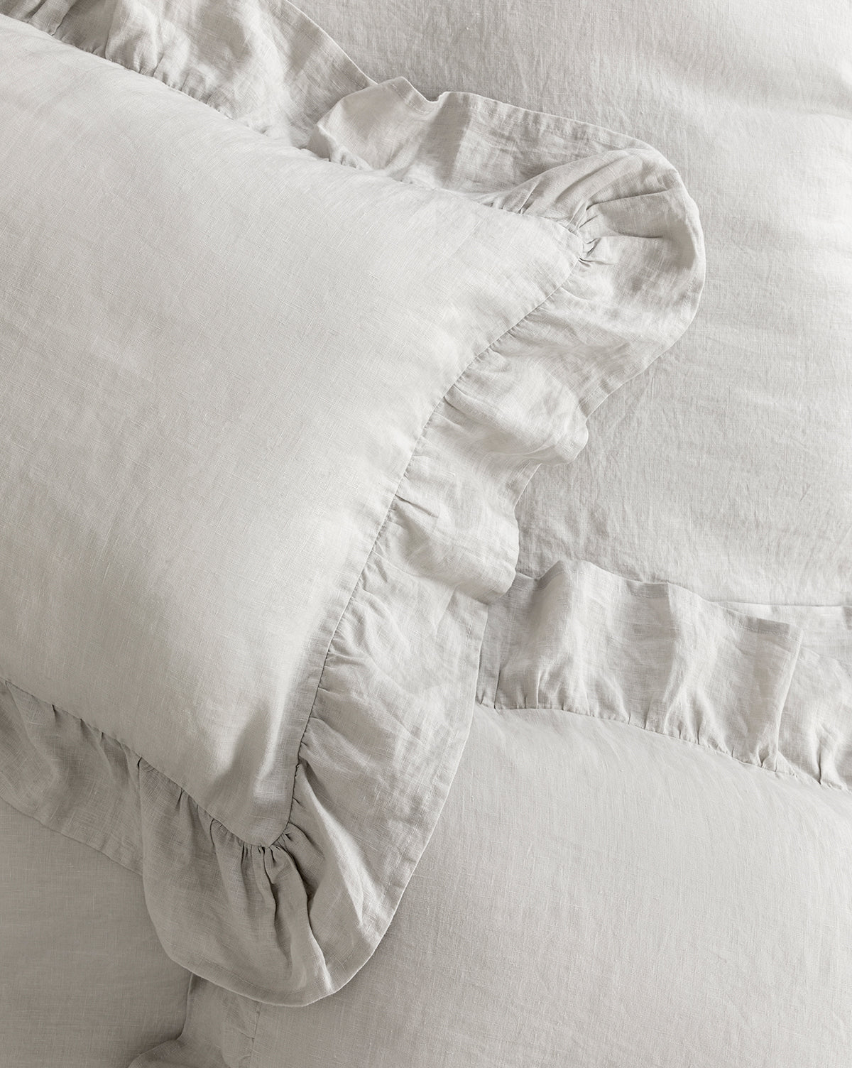 Close-up of light gray Ruffle Linen Shams (Set of 2), crafted from soft, textured fabric with elegant ruffled edges for a cozy, romantic bedding accent.