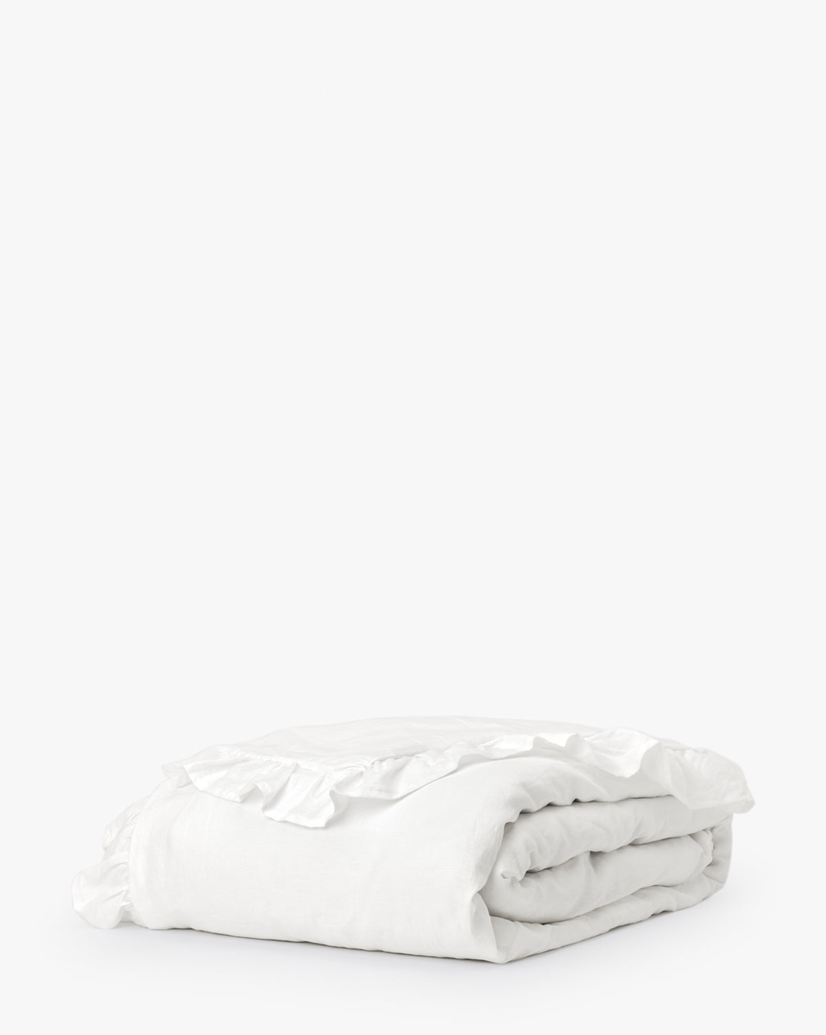 The Ruffle White Linen Duvet Cover, made from 100% linen bedding, features charming ruffled edges and a soft, elegant touch—shown neatly folded against a plain white background.
