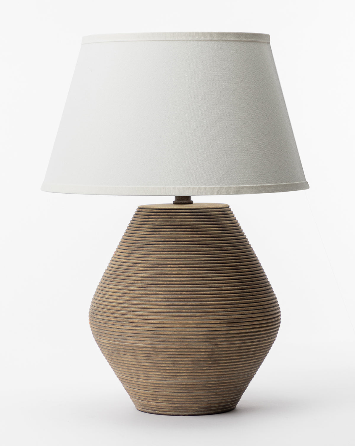 The Troy Lighting Rustco Table Lamp has a brown ceramic base with an earthen ribbed texture and a wide white fabric lampshade, shown against a plain white background. McGee & Co.