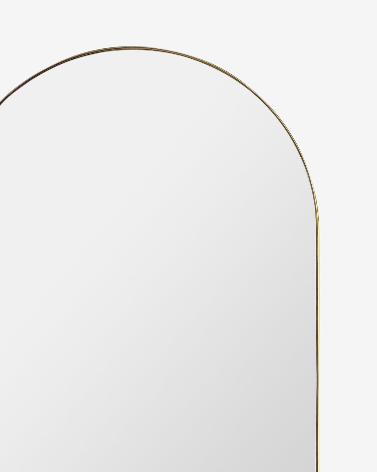The Rye Wall Mirror, featuring a large arched shape and a slim gold stainless steel frame, is displayed against a plain white background, by McGee & Co.