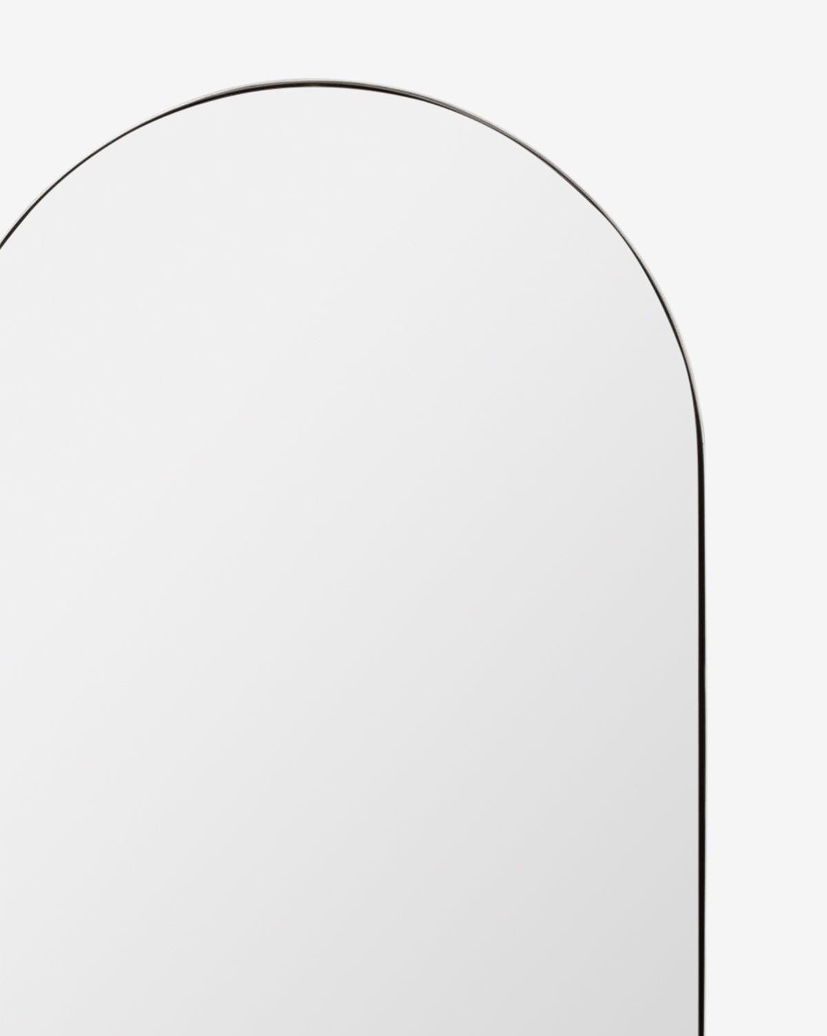 A close-up of the Rye Wall Mirror’s top left section, showing its tall, rounded rectangular shape and slim black frame set against a white background, by McGee & Co.