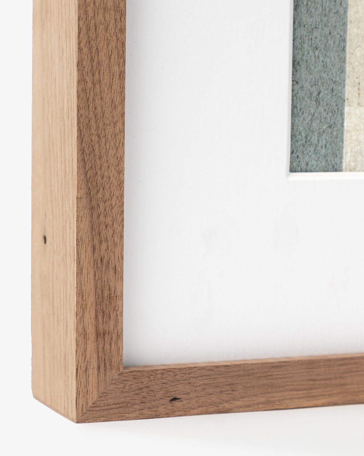 Close-up of the corner of a rustic walnut frame with a white mat board and natural wood grain, complementing the abstract artwork Safe by Dan Hobday.
