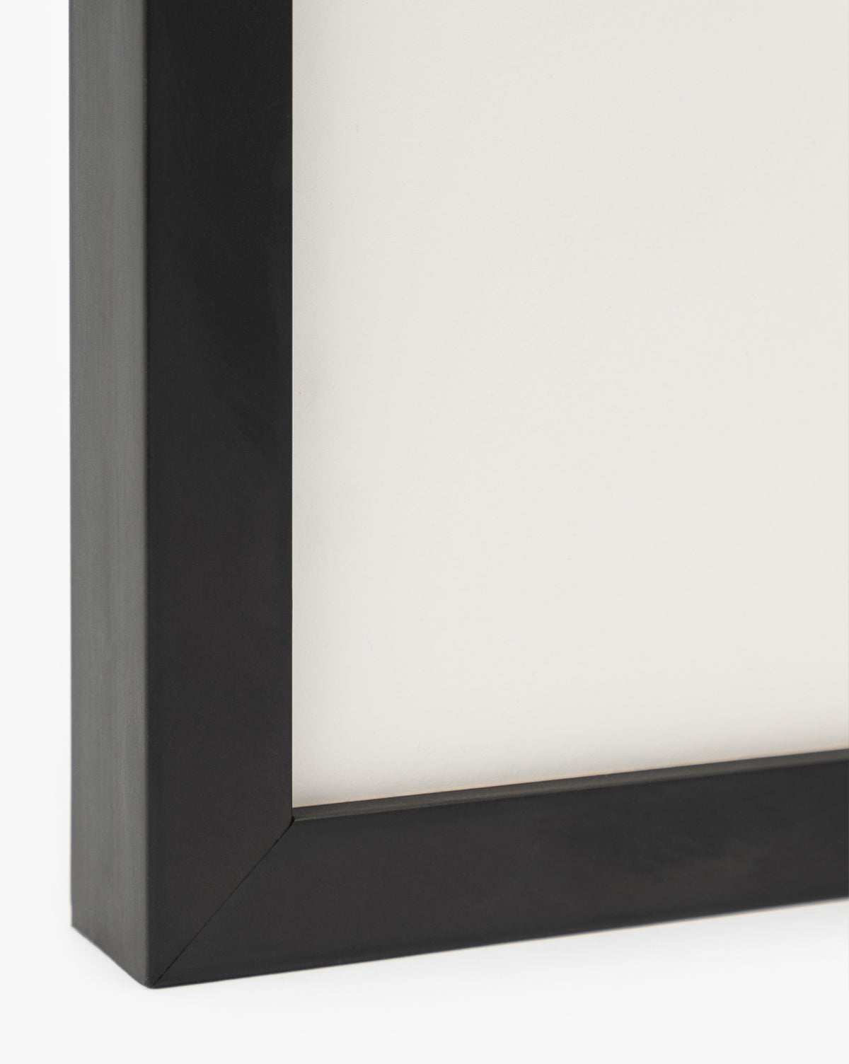 Close-up of the bottom left corner of a black wood frame with a white background—perfect for displaying Sail Away watercolor wall art or small ship-themed pieces, by McGee & Co.