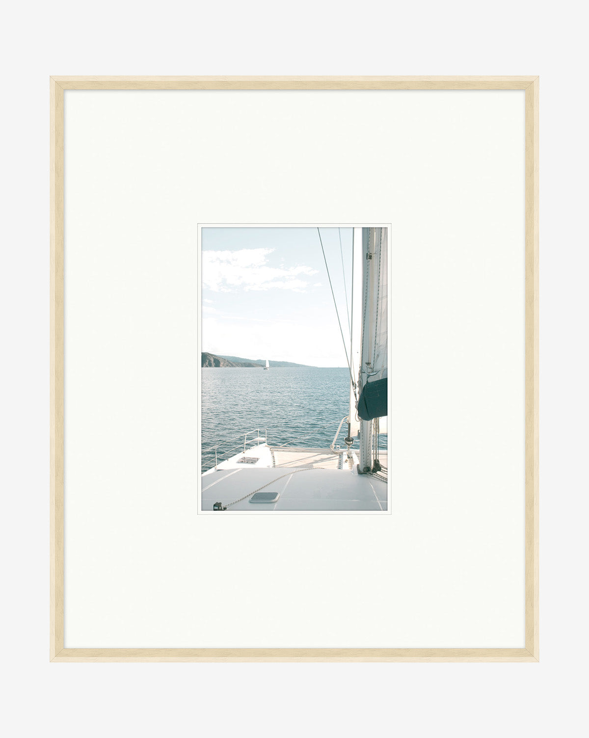 Sailboat Perspective is a framed photography print featuring a sailboat deck on calm water beneath a clear, partly cloudy sky, presented with a wide white mat and light pickled white frame—an ideal decorative wall art piece.