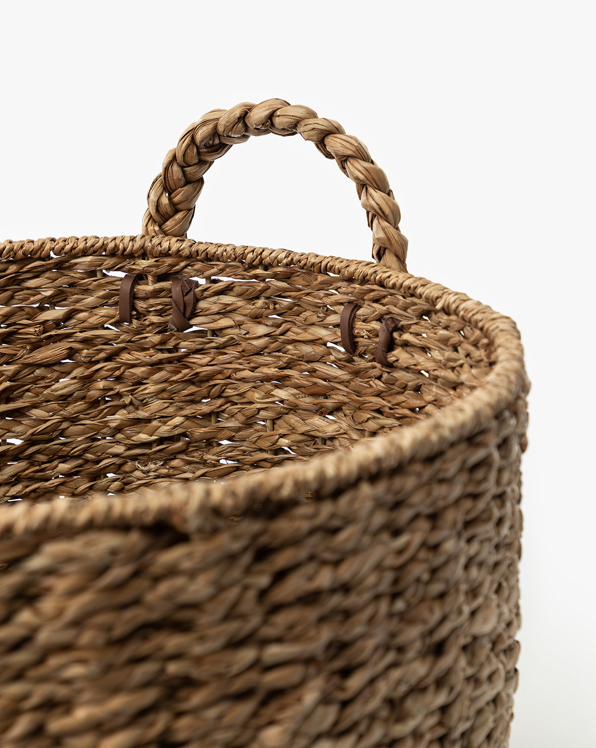 A close-up of the Salter Woven Basket, featuring a round shape, braided handle, and textured seagrass surface, set against a plain white background, by McGee & Co.