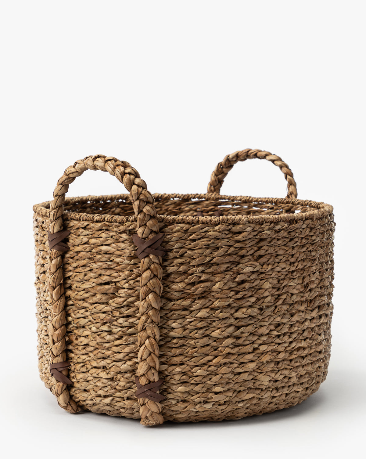 The Salter Woven Basket is a round seagrass storage basket with natural fibers and two thick, braided handles, featuring a rustic look against a plain white background, by McGee & Co.