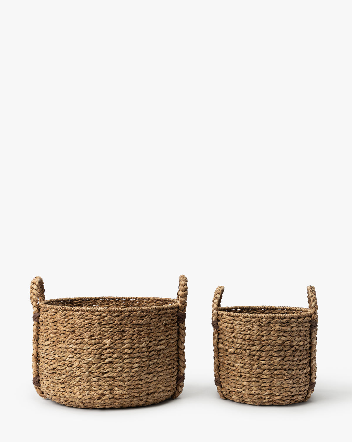 Two Salter Woven Baskets with handles, crafted from natural fibers, are side by side on a white background. The larger basket is on the left and the smaller one is on the right, by McGee & Co.