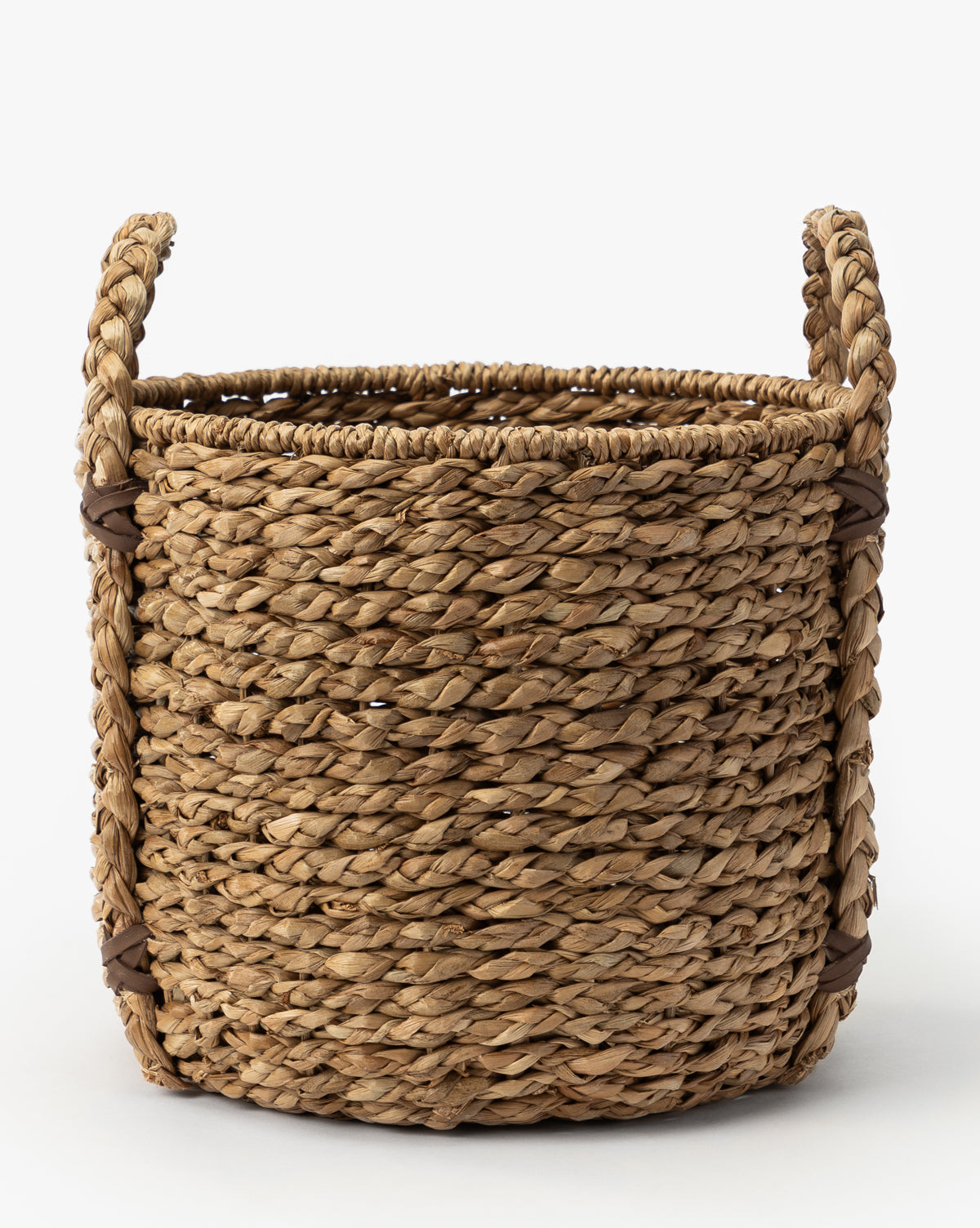 The Salter Woven Basket is a round storage basket crafted from natural seagrass fibers, featuring two sturdy side handles and shown on a white background, by McGee & Co.