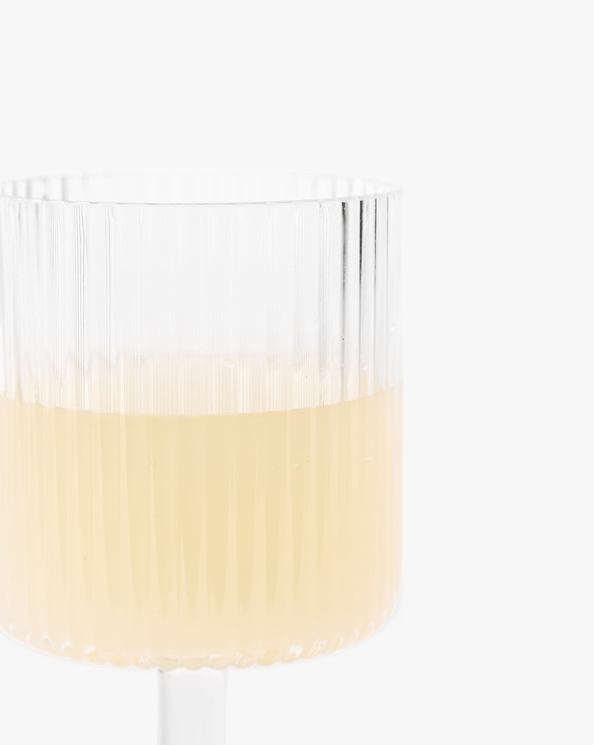A Sanibel Acrylic Goblet from the set of 4, featuring a ribbed design and filled halfway with a light yellow beverage, is displayed against a plain white background.