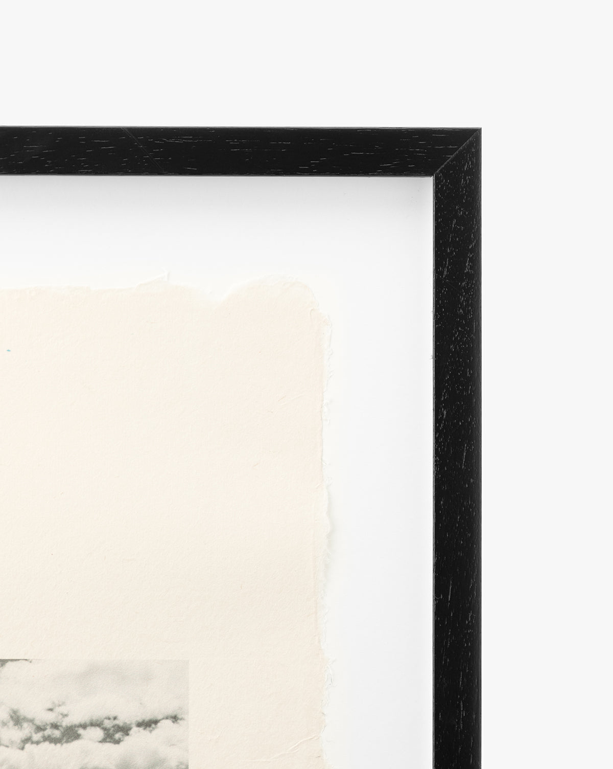 Close-up of the top right corner of the black Santa Cruz picture frame with textured, torn-edge paper and a glimpse of a vintage coastal scene photo at the bottom left, set against a plain white background.