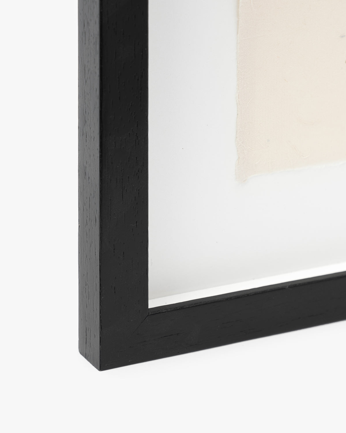 Close-up of the bottom left corner of the black wooden Santa Cruz picture frame with a white mat and beige artwork inside, evoking vintage wall art and echoing a calm coastal scene.