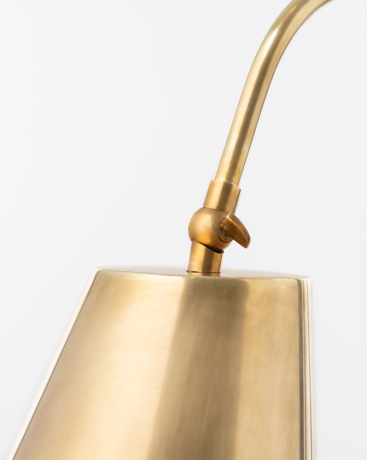 Close-up of the Saylor Floor Lamp, featuring a curved arm and adjustable joint. The elegant brass lamps brushed matte finish highlights its refined modern design against a plain white background, by McGee & Co.