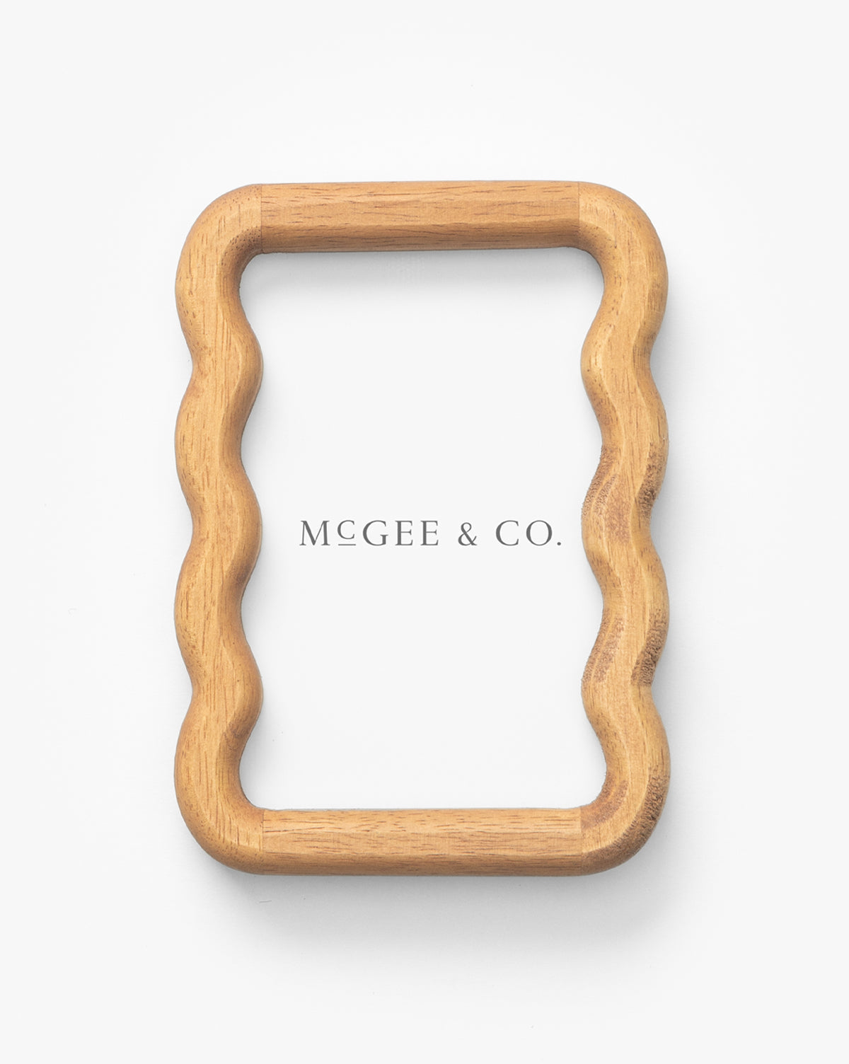 A rectangular Scalloped Wood Frame with gently wavy sides is crafted from natural rubberwood and displayed on a white background. Scalloped Wood Frame is centered inside, making it an elegant addition to your interior decor by McGee & Co.