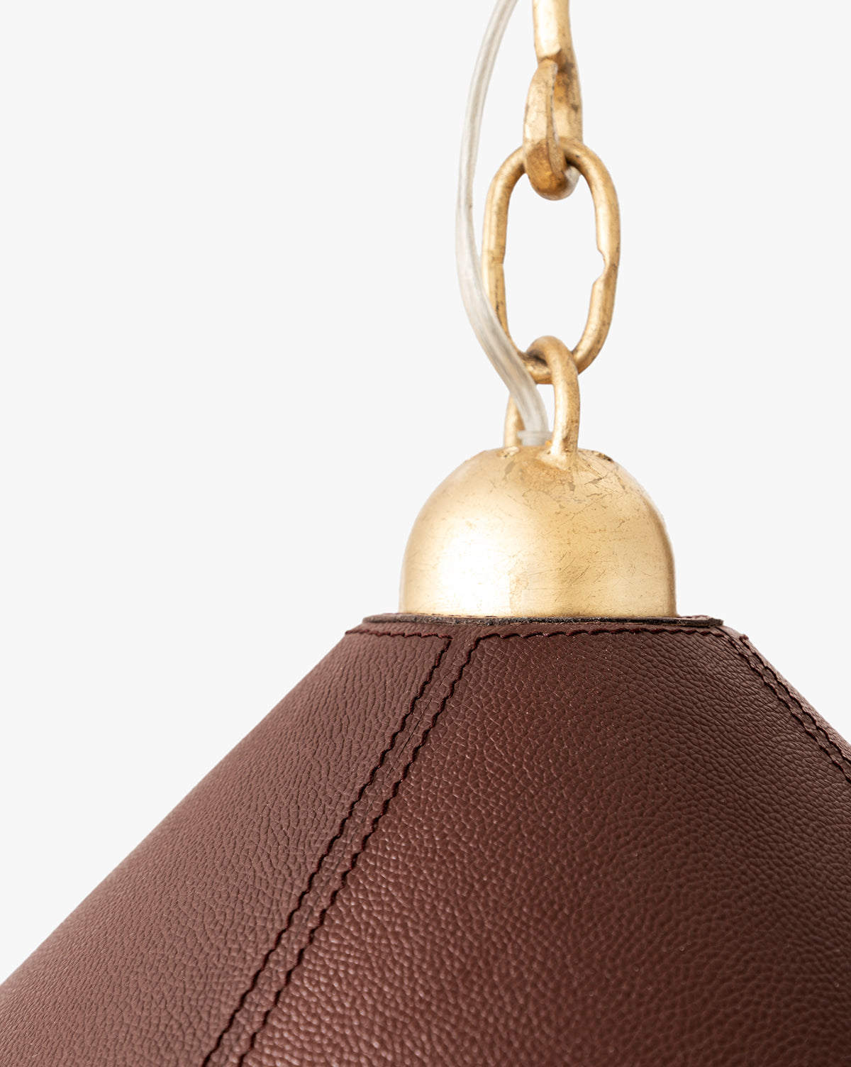 Close-up of the Scarlett Pendant, an elegant light with brown textured leather and visible stitching, topped by a gold leafed iron cap and chain, shown against a plain white background, by McGee & Co.