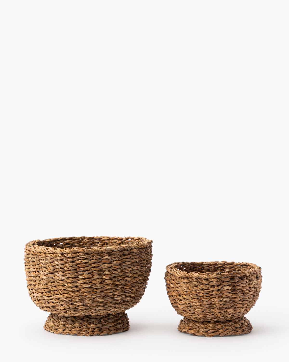 Pair of Seagrass Footed Bowls in two sizes, crafted from woven natural materials with wide bases and subtly flared rims, displayed side by side on a white background for a decorative touch.