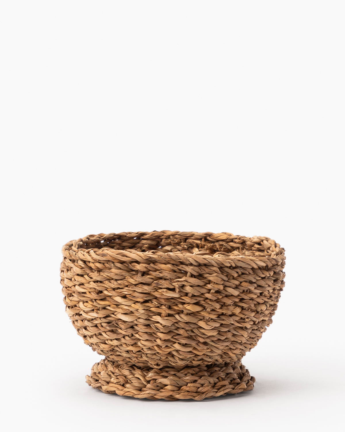 The Seagrass Footed Bowl is a small, round bowl made from natural brown seagrass fibers. It features a wide opening, a sturdy flared base, and elegant natural detailing—perfect as a decorative accent.
