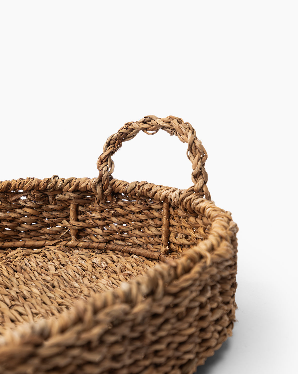 Close-up of the Seagrass Oval Tray, featuring thick, textured straw and a braided handle, with natural woven details reminiscent of a decorative basket, set against a plain white background.