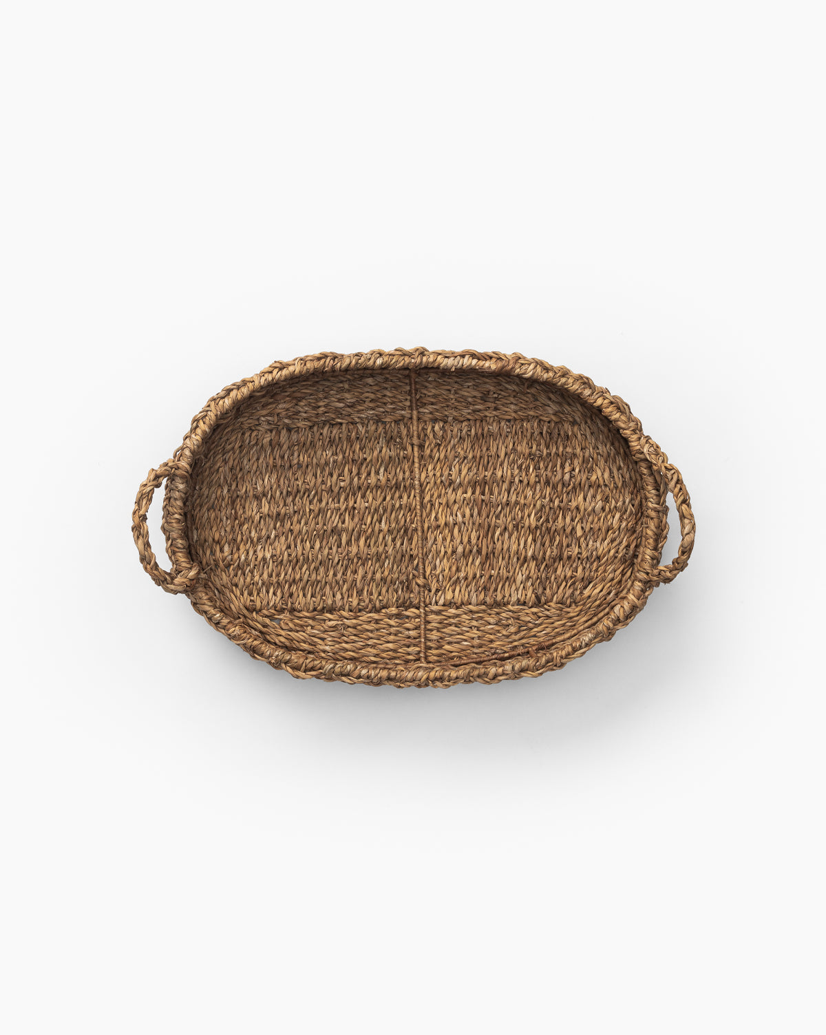 The Seagrass Oval Tray features natural woven wicker, two handles, and is beautifully displayed from above on a white background.
