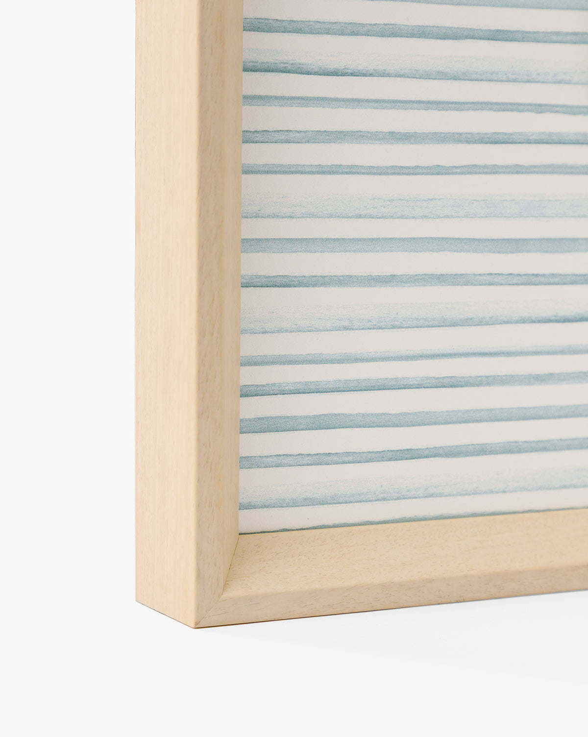 Close-up of the corner of the Seaside Village light wooden frame, featuring abstract horizontal blue and white stripes—perfect for adding coastal charm to any space, by McGee & Co.