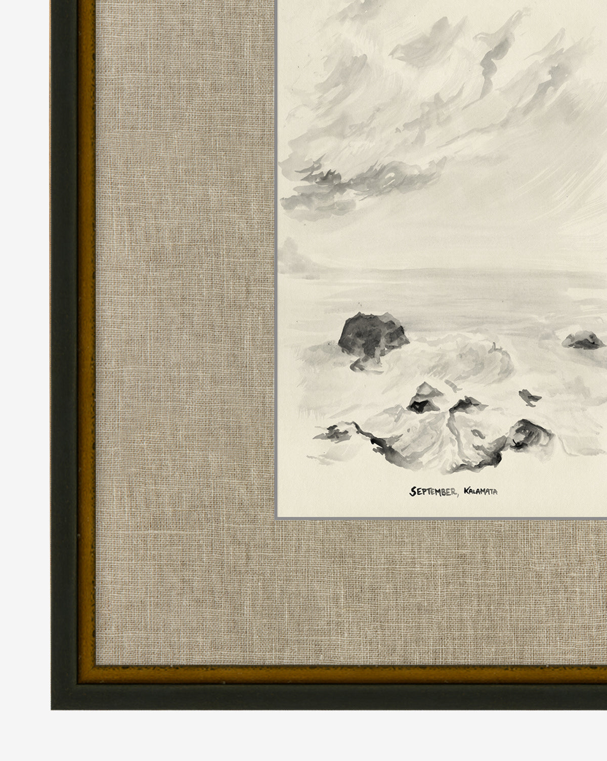 Framed black-and-white painting titled September in Kalamata depicts a rocky seashore beneath a cloudy sky. Signed in the bottom right corner, it features a hand-wrapped linen mat and a dark wooden border.