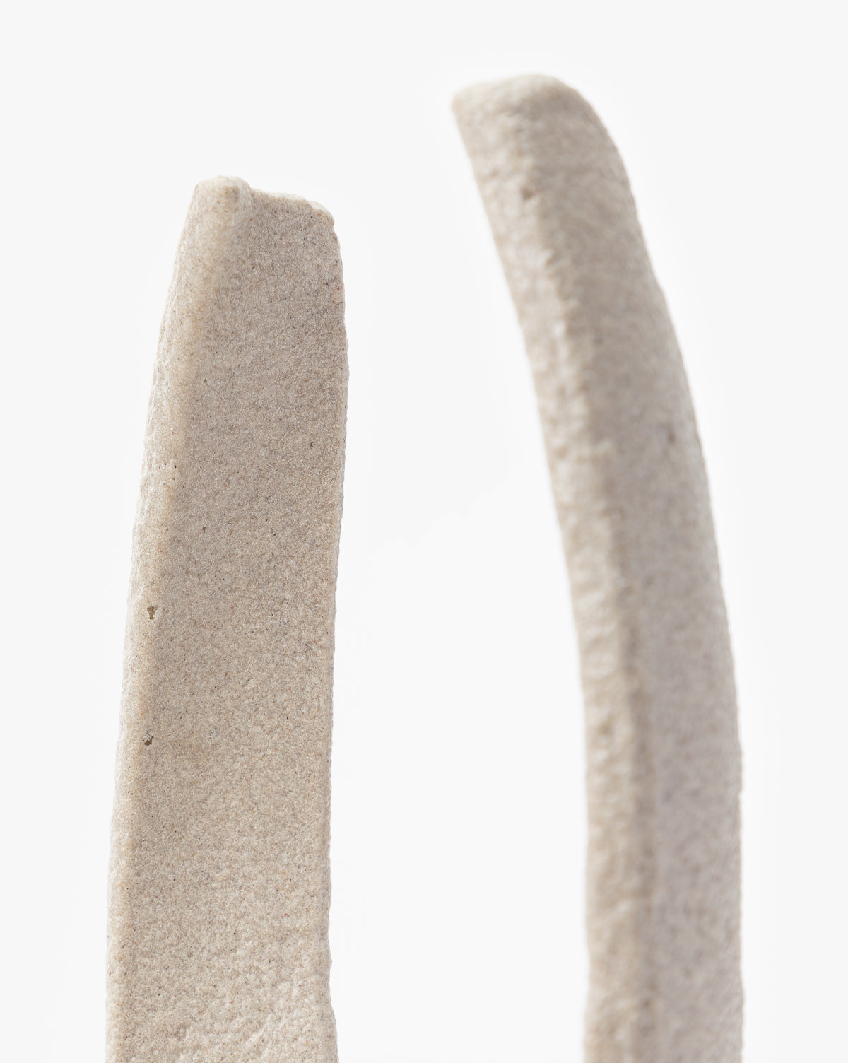 The Sergio Objects are two upright, textured, light beige pieces with minimalist forms—one straight and one gently curved—perfect for contemporary decor and displayed together on a plain white background.