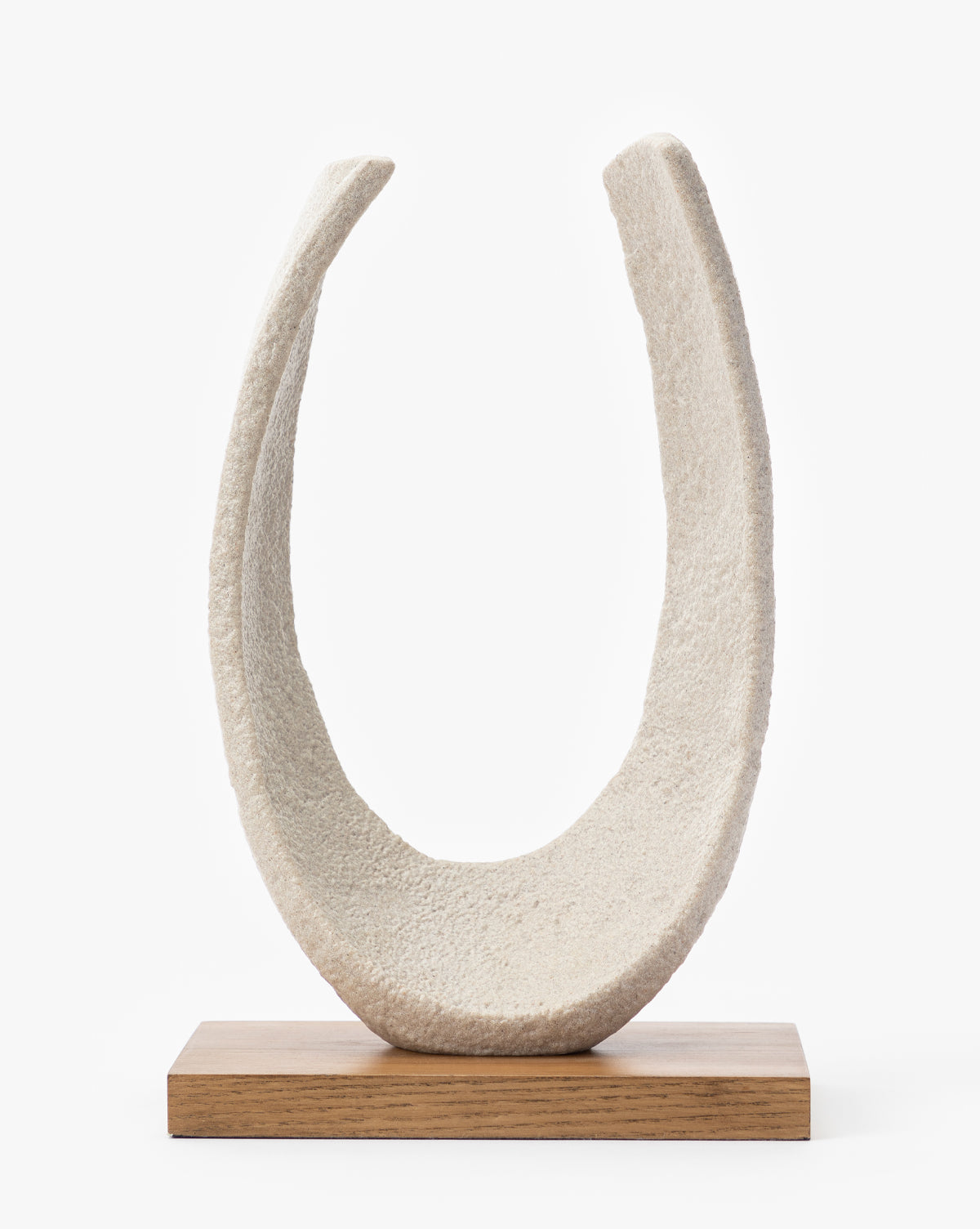 The Sergio Object is a textured, off-white U-shaped resin sculpture set upright on a rectangular ash wood base, making it a striking piece of contemporary decor against a plain white background.