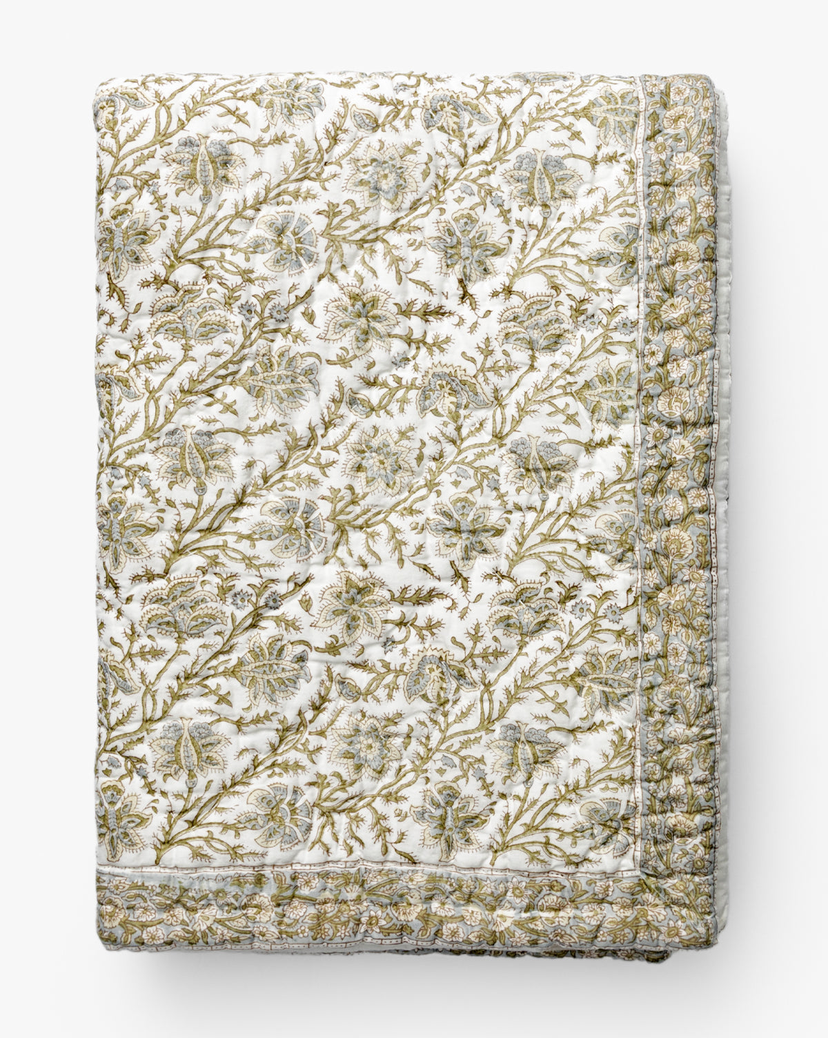 The Renuka Inc. Seton Kids Quilt features an intricate gold and green floral pattern on white, with stitched details and a decorative border, all neatly folded for display by McGee & Co.