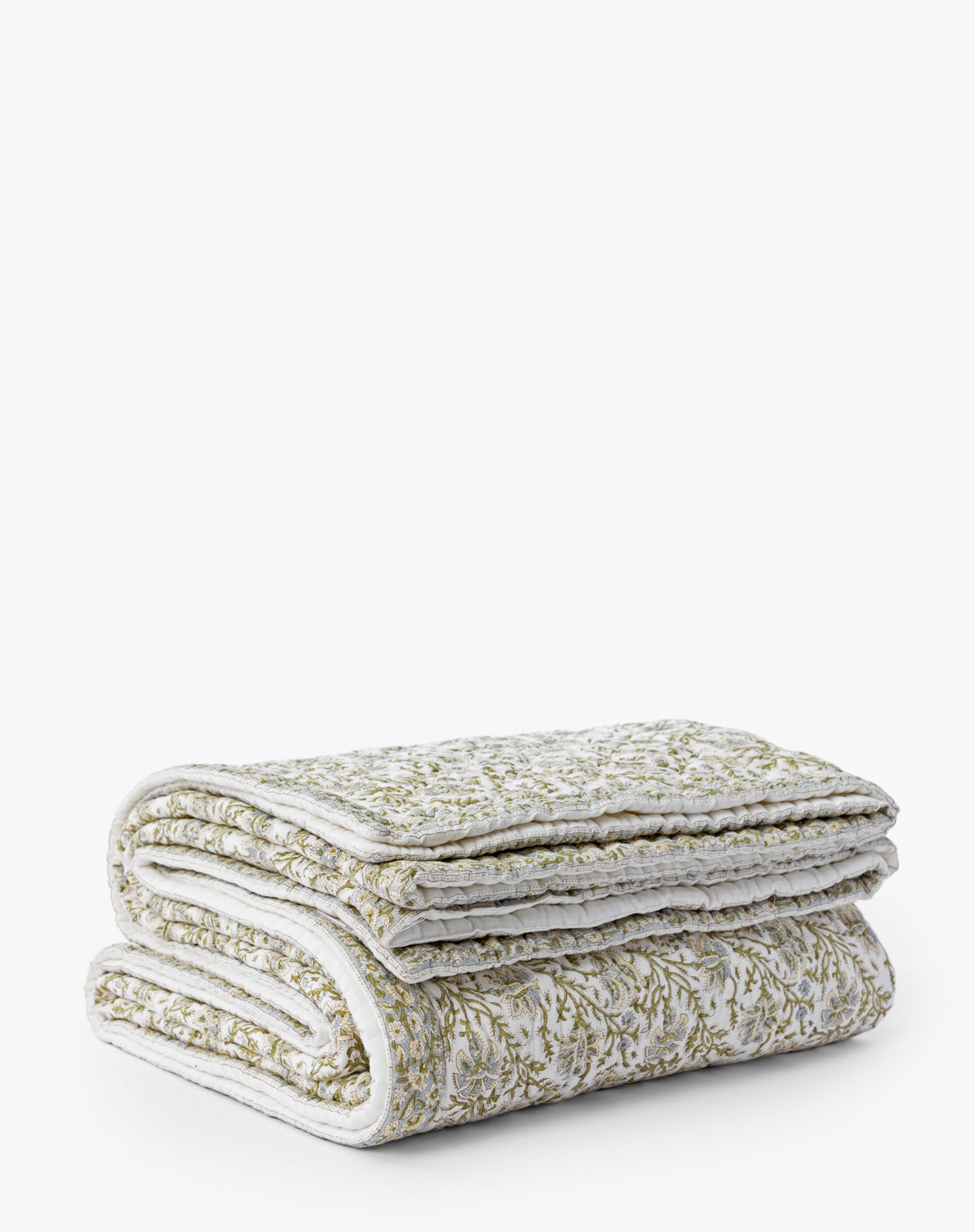 The Seton Kids Quilt by Renuka Inc. is a neatly folded, quilted blanket featuring a subtle white and green floral pattern, shown against a plain white background — McGee & Co.