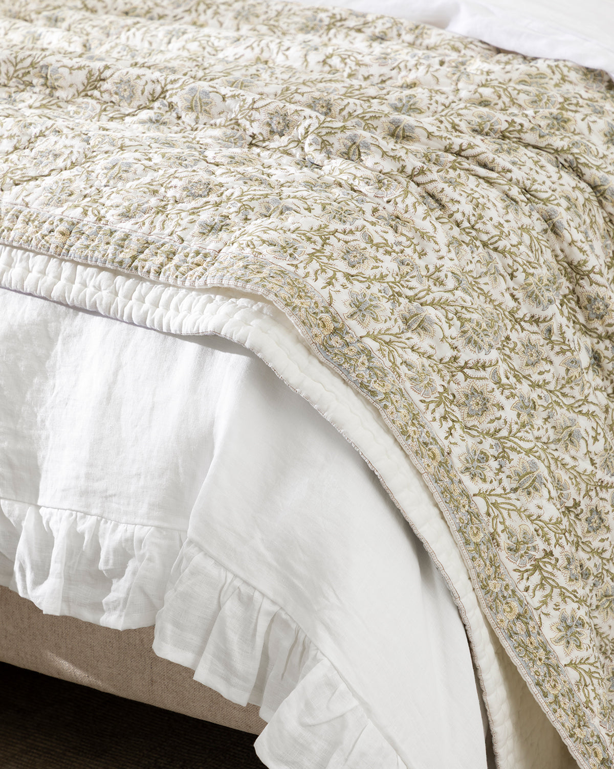 The Seton Kids Quilt features delicate vine patterns in earthy green and beige tones, and is paired with a white ruffled bed skirt for a charming, nature-inspired look, by McGee & Co.