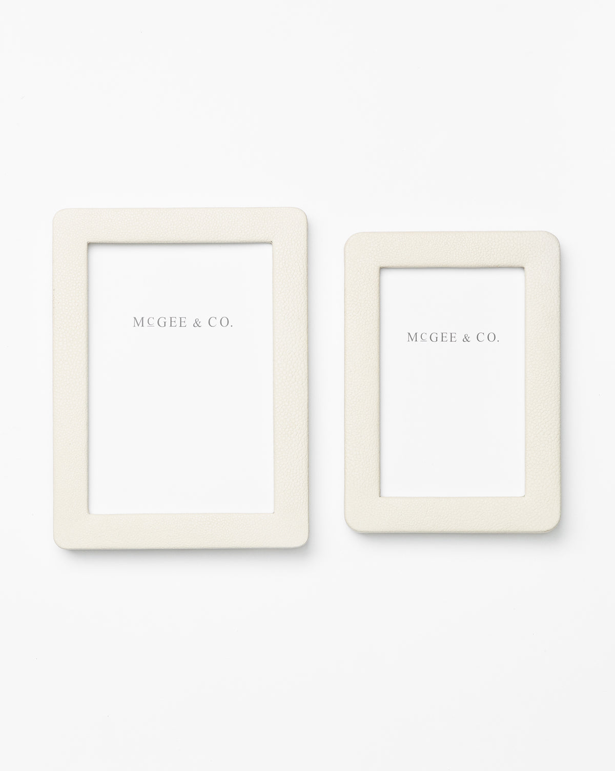 Two cream-colored Shagreen Picture Frames in different sizes, featuring shagreen leather details and white MCGEE & CO. inserts, are displayed on a plain white background for an elegant look.