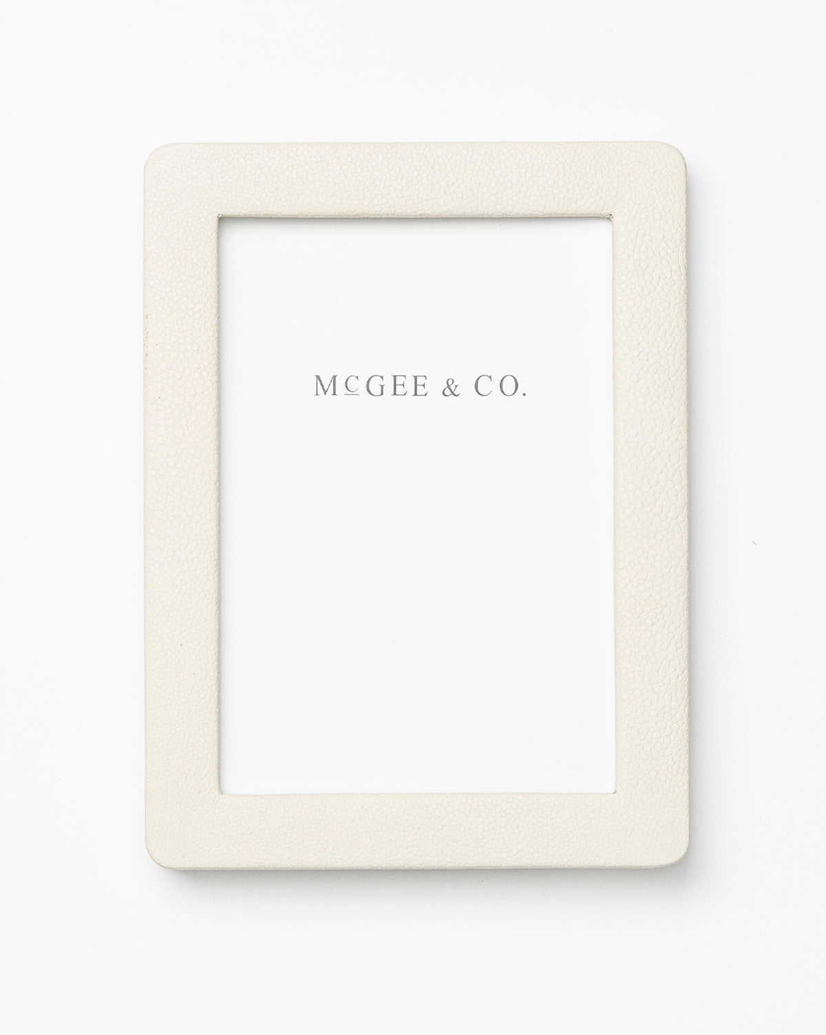 The Shagreen Picture Frame is a plain, rectangular off-white frame with a textured shagreen finish. It features a white insert with MCGEE & CO. centered, and is elegantly displayed on a white background.