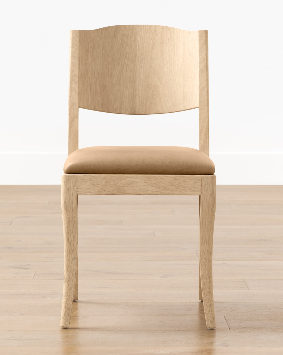 The Shepherd Dining Chair features a curved backrest and a tan upholstered seat, displayed on a wooden floor with a plain white wall background by McGee & Co.